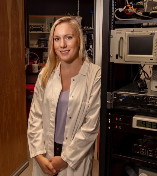Stacey standing next to electrophysiology rig